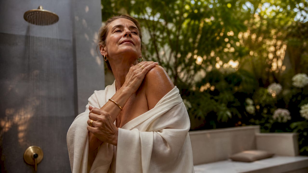 Woman applying skincare in elegant bathroom